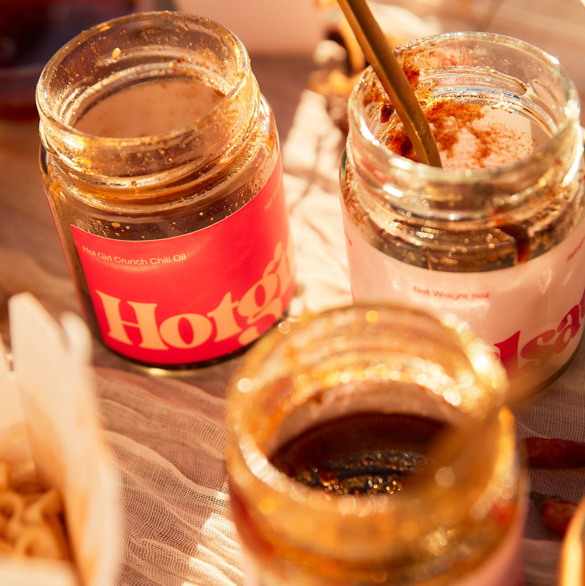 Open jars of OG Hot Girl Chili Oil and Hot Girl Crunch Chili Oil on a sunny table  - Hotgirlsauce chili oil - chili sauce - hot sauce