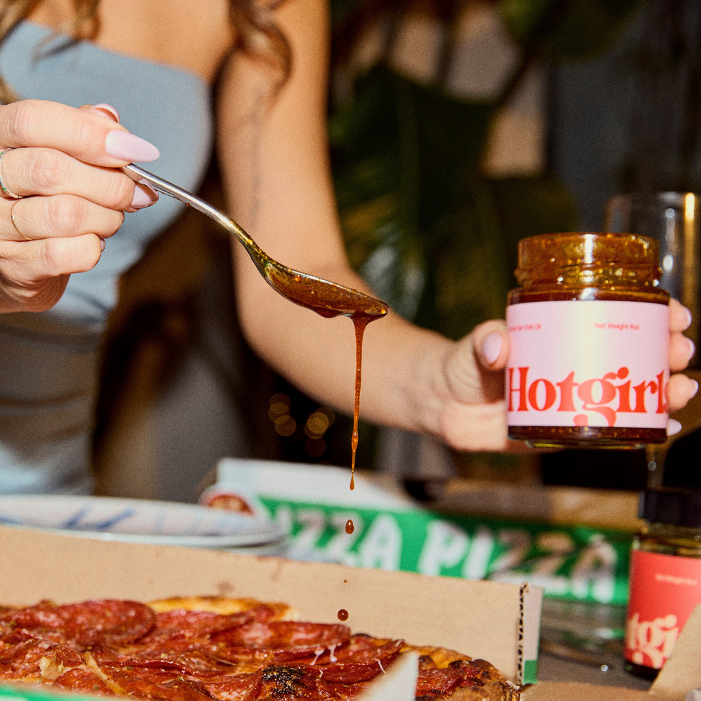 Woman drizzling OG Hot Girl Chili Oil hot sauce over a pizza -  Hotgirlsauce chili oil - chili sauce - hot sauce