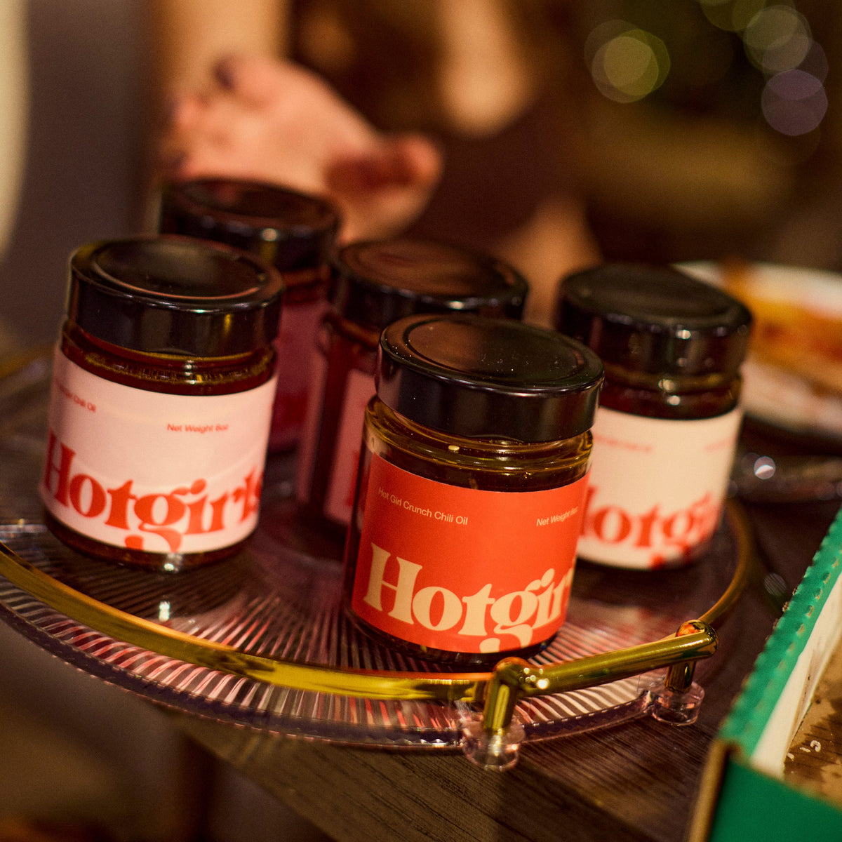 A vintage tray holding jars of an assortment of Hotgirlsauce flavors, like OG Hot Girl Chili Oil, Hot Girl Crunch Chili OIl, and Habanero Hot Girl Chili Oil -  Hotgirlsauce chili oil - chili sauce - hot sauce
