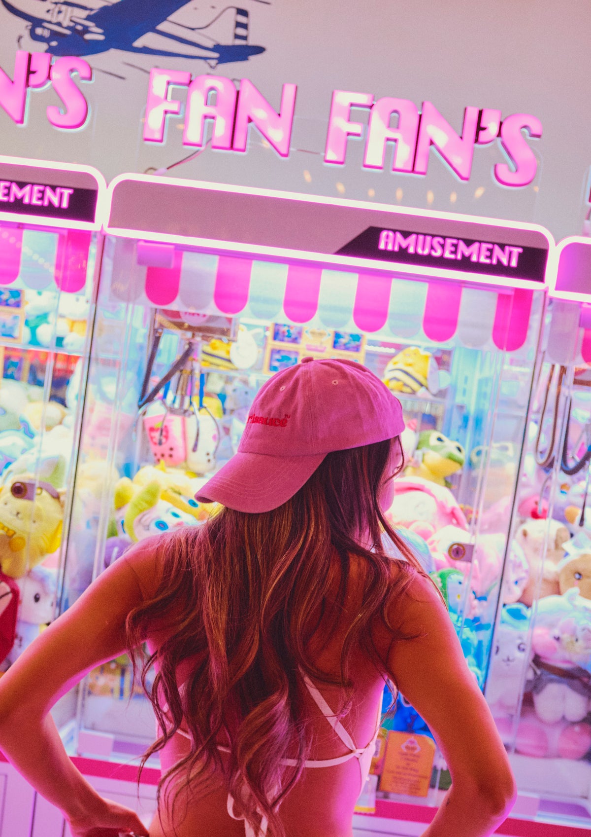 Woman in pink Hotgirlsauce hat posing in front of arcade machines