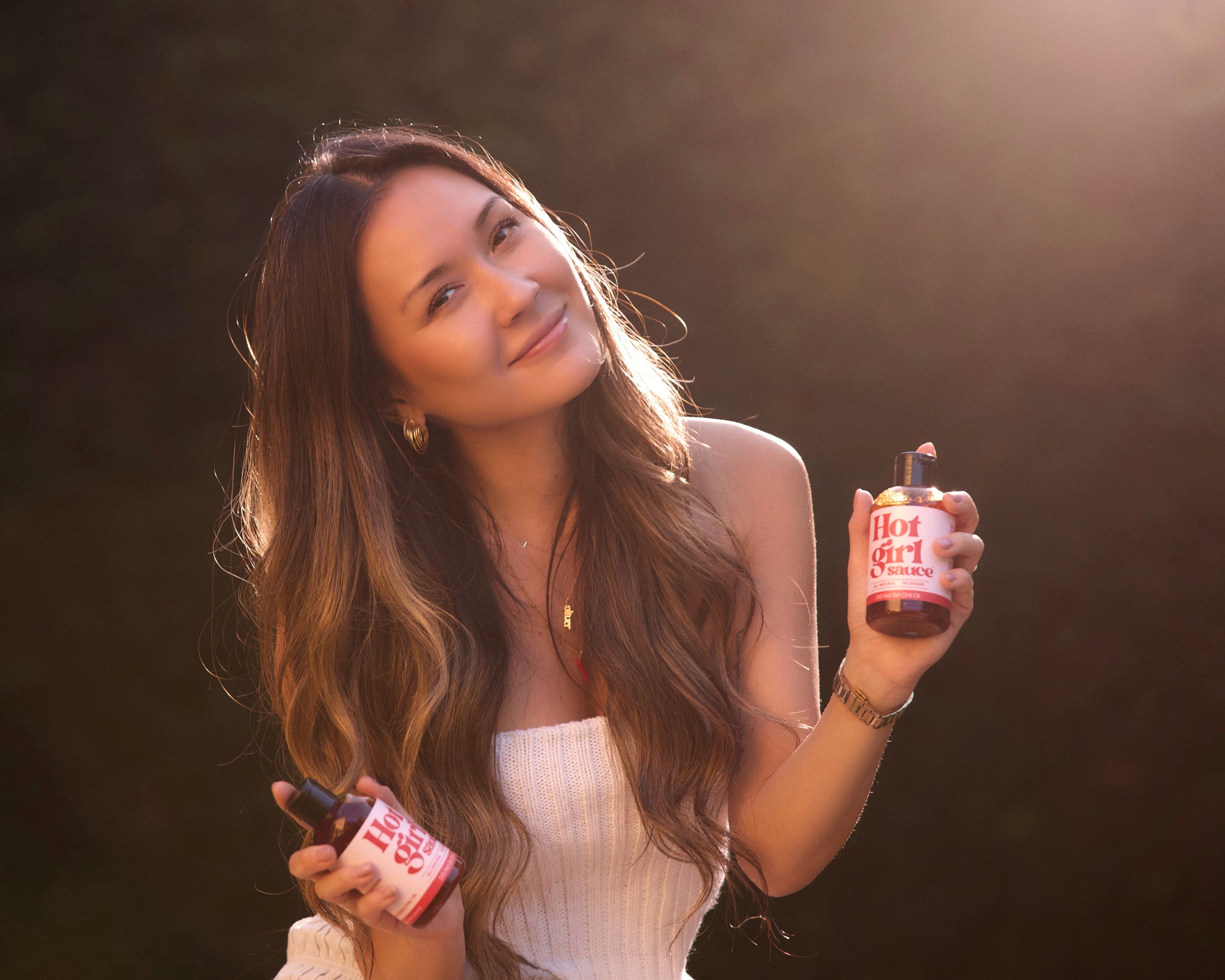 Hotgirlsauce founder Janice Miye Kim holding two bottles of OG Hot Gil Squeezable Chili Oil  -  Hotgirlsauce chili oil - chili sauce - hot sauce