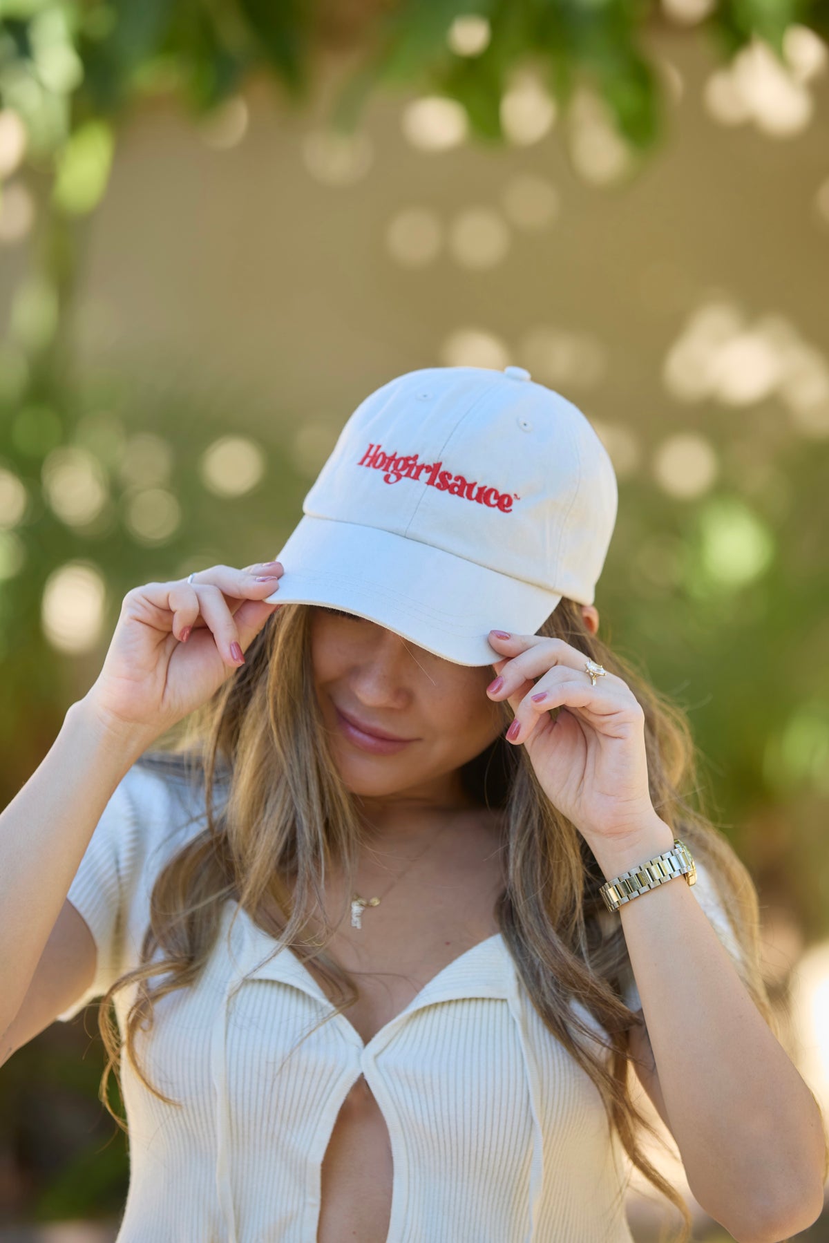 Woman adjusting Hotgirlsauce cream dad hat, everyday streetwear look