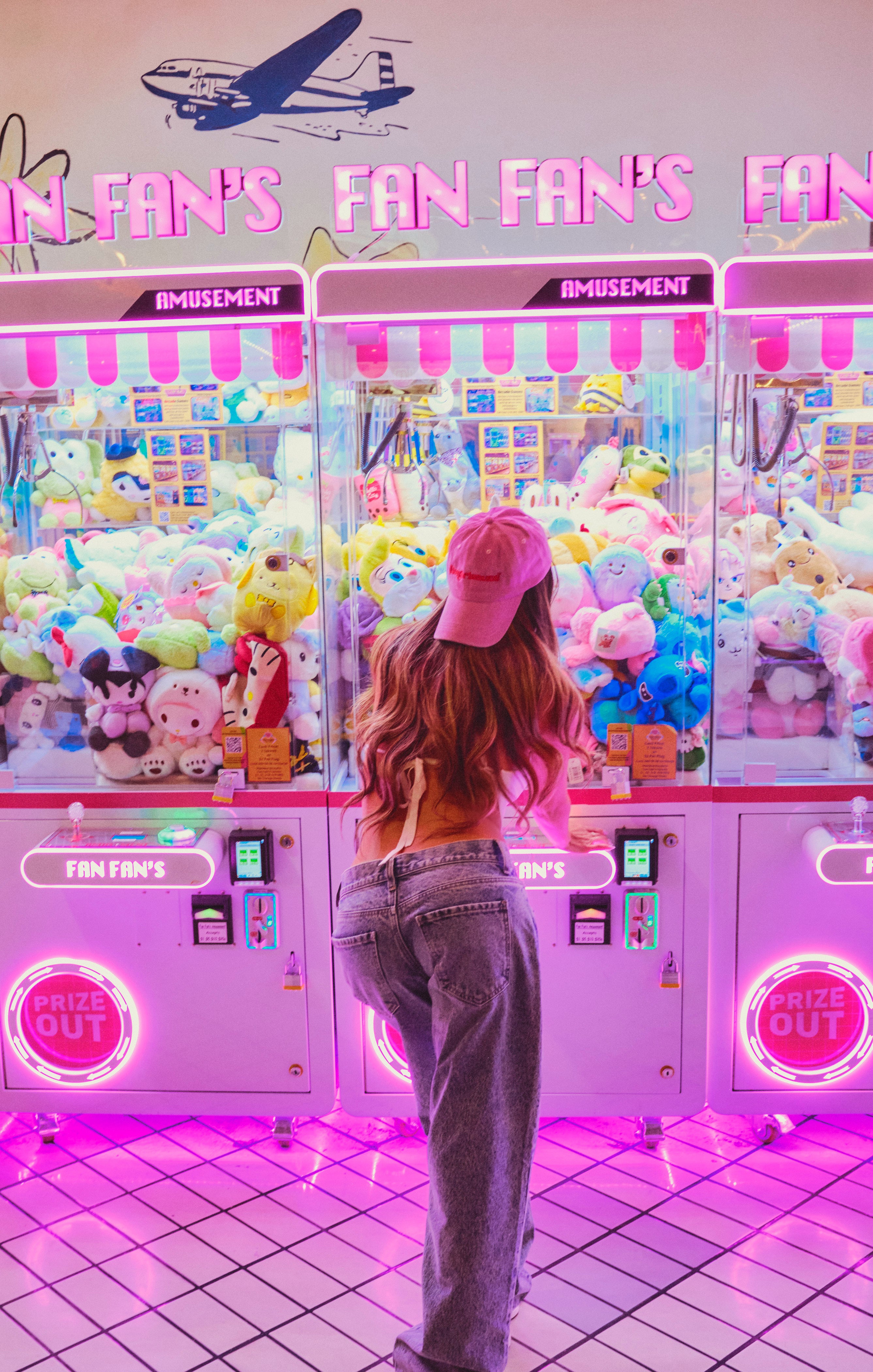 Woman wearing Hotgirlsauce pink dad hat standing in front of arcade games