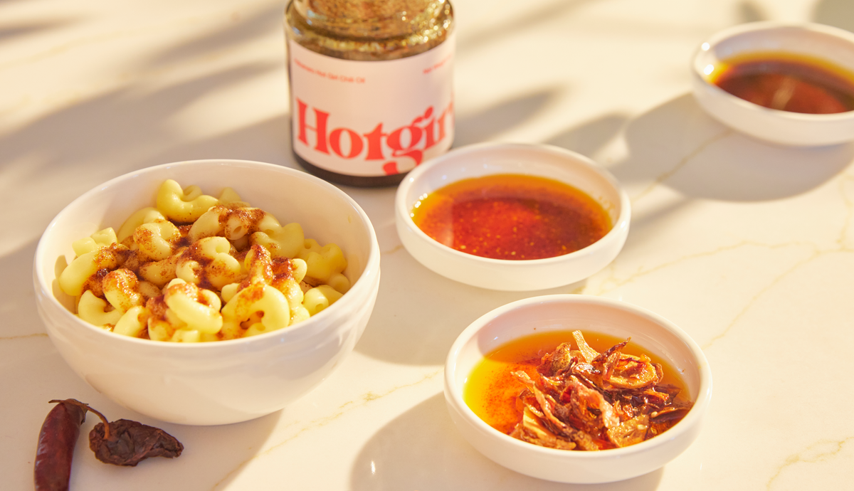 Mac and cheese drizzled in OG Hot Girl Chili Oil placed next to saucers of each Hotgirlsauce flavor  - Hotgirlsauce chili oil - chili sauce - hot sauce