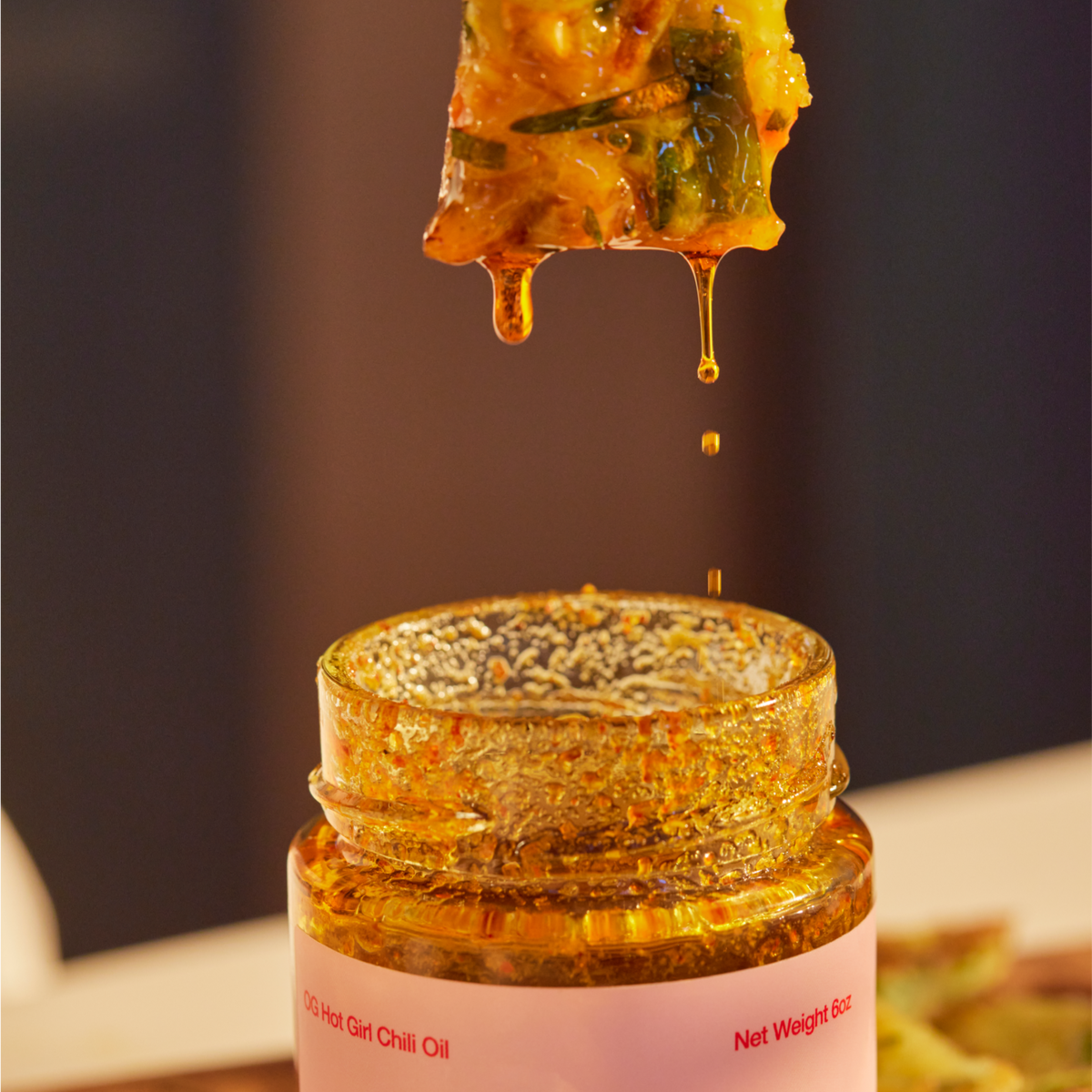 Vegetable pancakes dripping silky smooth  chili oil into a jar of OG Hot Girl Chili Oi - Hotgirlsauce chili oil - chili sauce - hot sauce