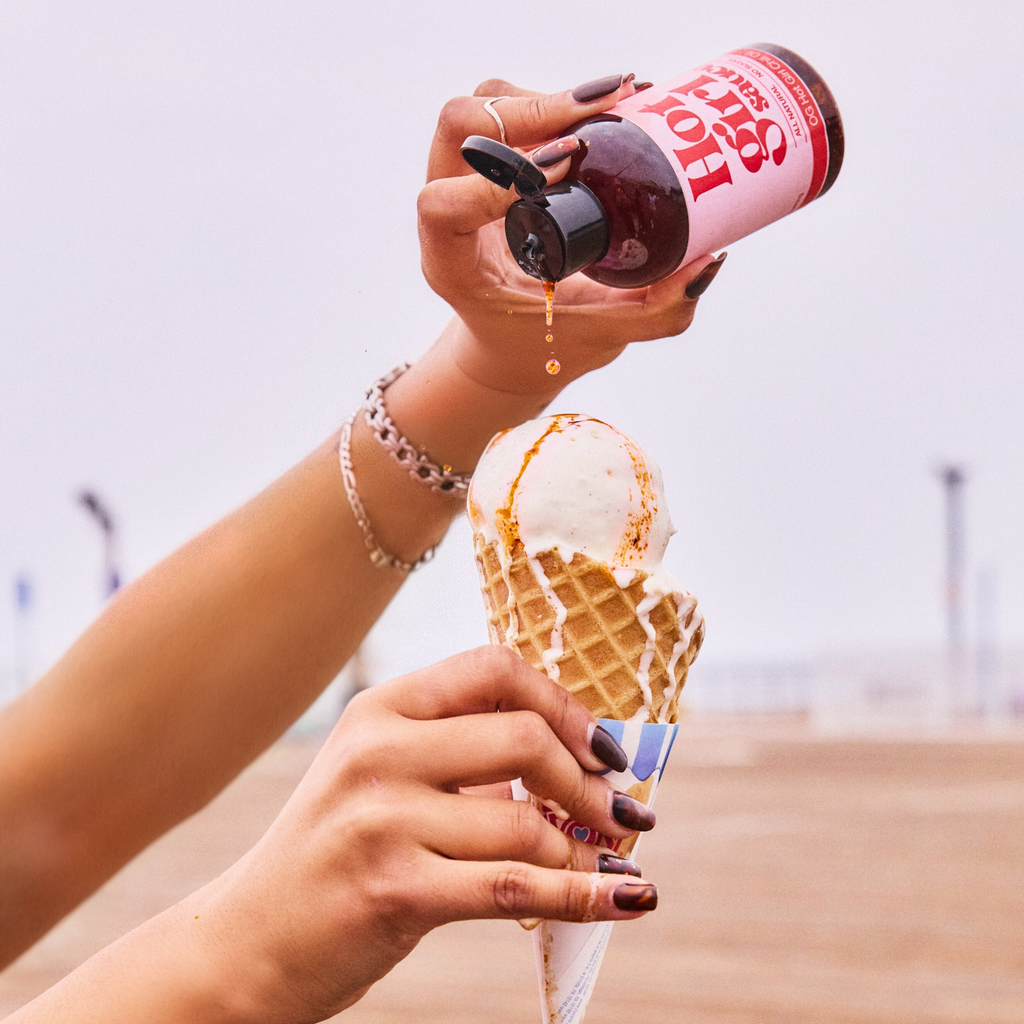 Woman squeezing OG Hot Girl Chili Oil over ice cream cone while at the pier by the beach -  Hotgirlsauce chili oil - chili sauce - hot sauce