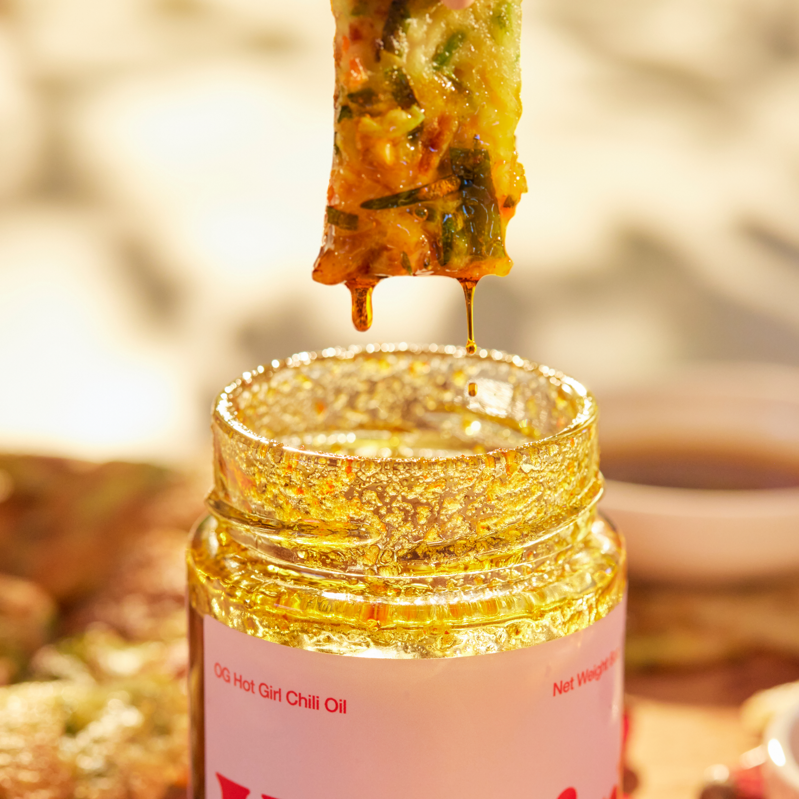 Vegetable pancake dripping silky smooth chili oil into a jar of OG Hot Girl Chili Oil  - Hotgirlsauce chili oil - chili sauce - hot sauce