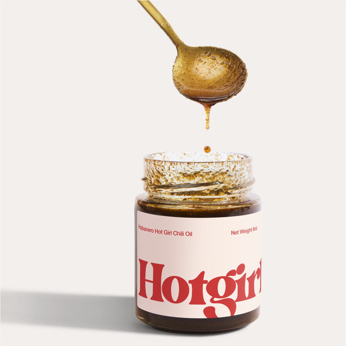 Spoon dripping silky smooth chili oil into  a jar of Habanero Hot Girl Chili Oil - Hotgirlsauce chili oil - chili sauce - hot sauce