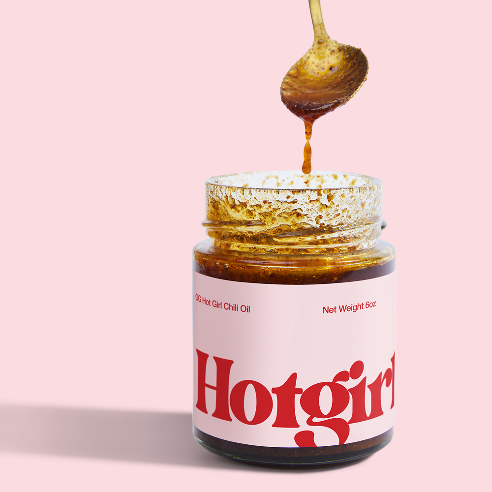 Silky smooth drips of chili oil falling from a spoon into a jar of OG Hot Girl Chili Oil - Hotgirlsauce chili oil - chili sauce - hot sauce 